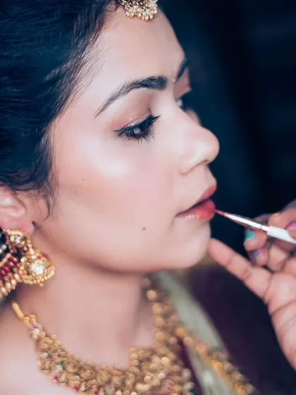 A makeup artist applying the final touch of lipstick, a classic getting-ready shot that we capture with an artistic eye.