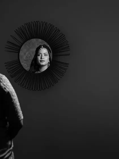 A creative black and white portrait using a mirror. The bride's reflection is captured, creating a thoughtful and artistic image about identity and transformation.