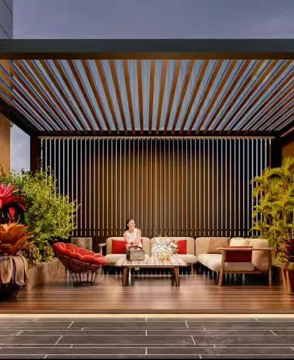 An elegant outdoor patio with a large pergola, creating a shaded lounge area. The space is beautifully landscaped with tropical plants, providing a luxurious resort-like feel.