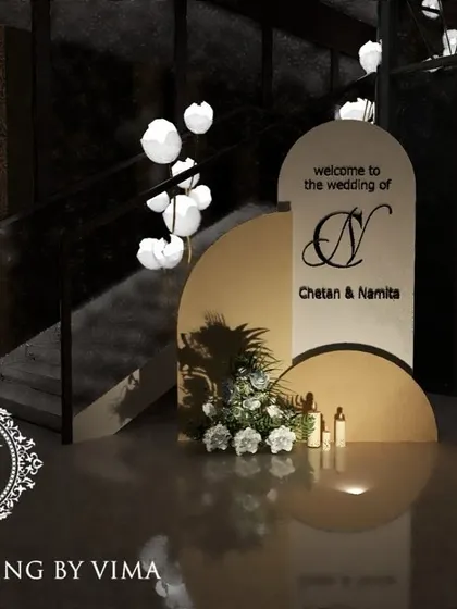 A classic and elegant reception setup symbolizing everlasting love. The stage features a modern, minimalist backdrop with custom monograms, floral arrangements, and soft lighting.