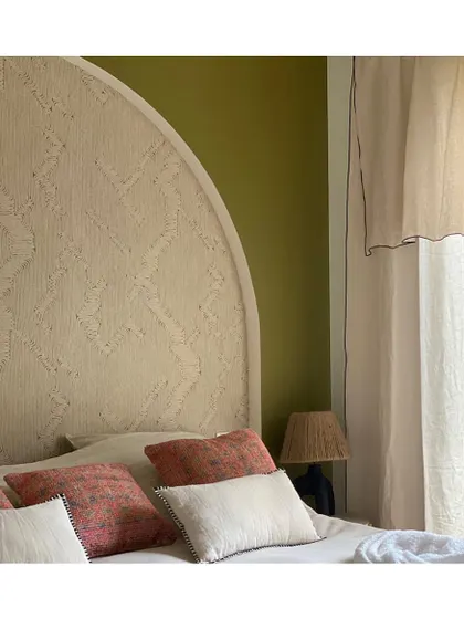 Wallpapers can be used in wonderfully creative ways, such as on this custom headboard. The 'Edge' wallpaper in a soft beige adds texture and a unique, architectural detail to this serene bedroom.