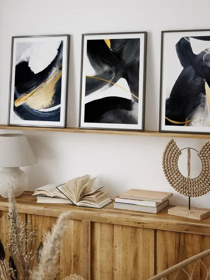 A dramatic set of three contemporary paintings with black and golden brushstrokes. This triptych creates a powerful and luxurious statement, perfect for a modern and sophisticated interior.