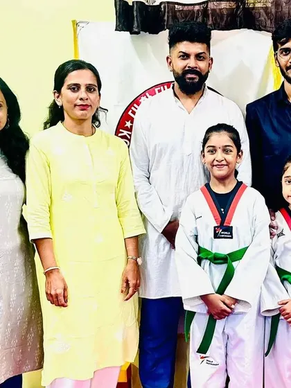 A family celebrates their daughters' new green belts.