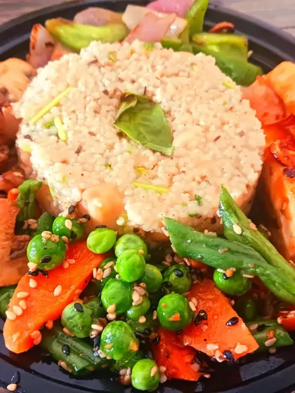 A close-up of the millet bowl, showing the colourful assortment of carrots, peas, and beans alongside seasoned tofu.