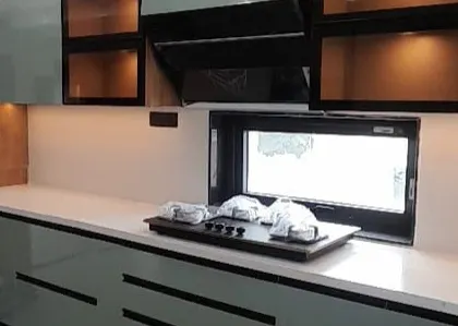 A close-up of a completed kitchen from another project. This view shows the under-cabinet lighting, sleek countertop, and glass-fronted upper cabinets, all elements of a modern, functional kitchen design.