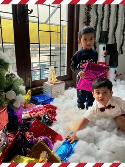 Two toddlers exploring the gifts under the tree, their faces full of curiosity.