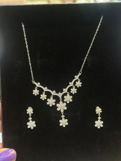 This is a delicate silver 925 necklace and earring set, featuring a floral design with sparkling stones. It's a lightweight and elegant choice for parties or as a special gift.