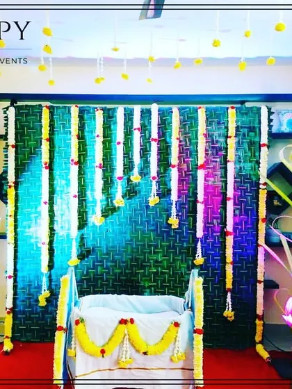 This is another angle of the home-based cradle ceremony decoration, showing the cradle and the natural, eco-friendly backdrop made from woven leaves and fresh flowers.