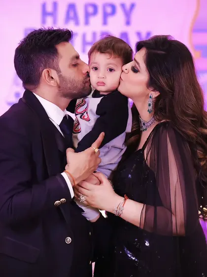 A loving family photo from a birthday party, with the birthday boy getting kisses from mom and dad.