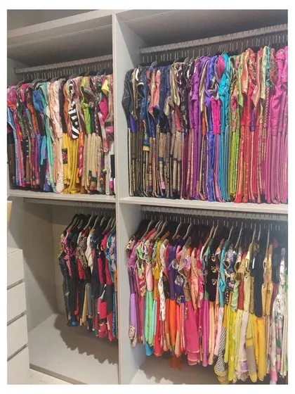 This walk-in closet was a fantastic project. Here you can see a huge collection of sarees and suits, all color-coded and hung on uniform hangers to create a boutique-like feel at home.