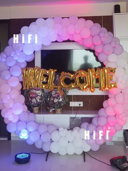 A beautiful welcome decoration for a housewarming or homecoming event. This large circular balloon arch in shades of pink and white frames a 'WELCOME' foil balloon sign, creating a warm and inviting entrance for guests.