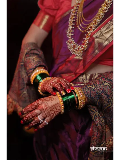 The bride's hands, rich with the color of mehndi and adorned with traditional jewelry, are a story in themselves.