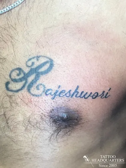 A chest tattoo of the name "Rajeshwori" with a large, decorative initial 'R'.