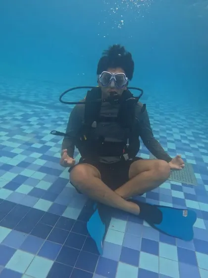 Find your moment of calm beneath the surface. This shot from our introductory scuba diving course in Malpe shows a participant mastering buoyancy and breathing techniques in the controlled environment of a swimming pool, the first step to underwater exploration.