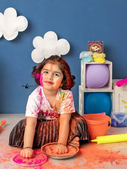 A sweet, colorful portrait of a girl enjoying the Holi setup in the studio.