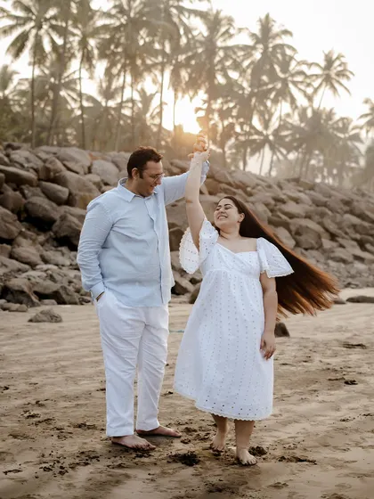 A beautiful, dynamic shot of a couple dancing on the beach at sunrise. The soft light and her twirling dress create a magical pre-wedding moment.