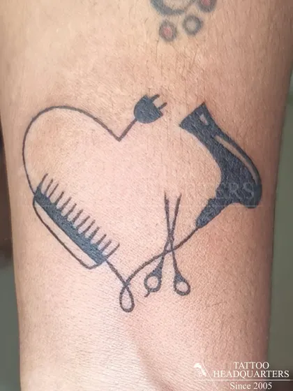 A creative heart-shaped tattoo for a hairstylist, made from a comb, scissors, and a hairdryer.