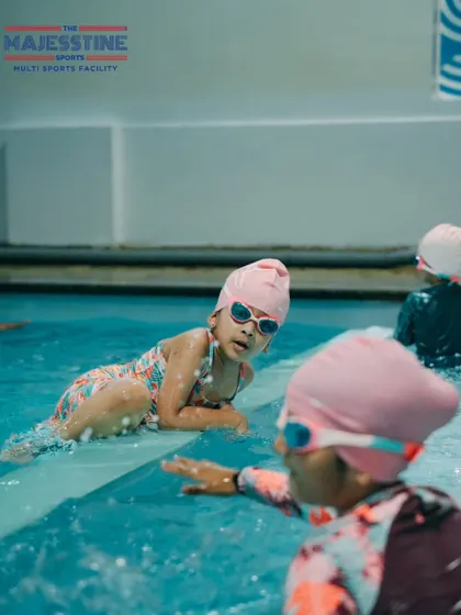 Learning to swim is a journey we take together. Here, a young swimmer takes a break at the edge of the pool, guided and encouraged by her coach and peers.