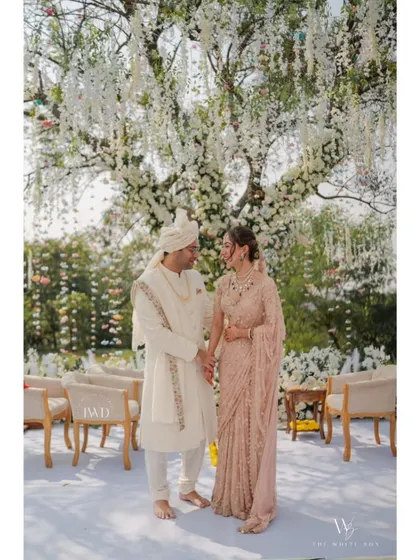 A portrait of pure elegance. The couple shares a quiet moment after their vows, standing under a canopy of white wisteria. Their coordinated pastel outfits and the serene garden setting create a picture of timeless romance.