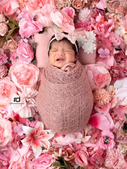 Even a little cry can be a beautiful moment to capture. Surrounded by a bed of pink flowers, this newborn's expression is so real and precious.