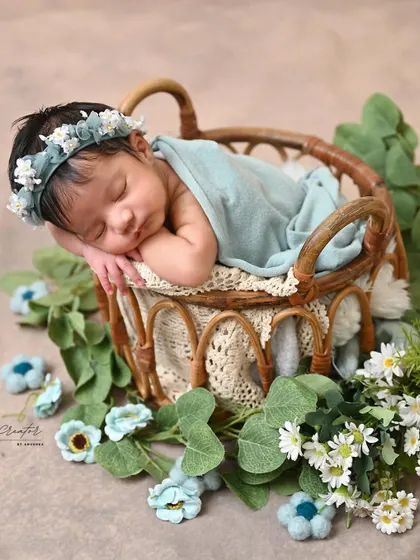 The perfect side-sleeper pose. This classic newborn portrait showcases the baby's delicate features as she naps in a basket adorned with flowers.
