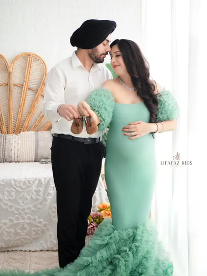 A classic shot that tells a story of anticipation. The couple holds up a tiny pair of baby shoes, their expressions full of hope and excitement for the future.