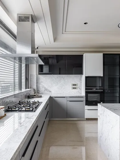 The L-shaped layout and large island provide ample counter space for cooking and entertaining, while large windows ensure the kitchen is filled with natural light.