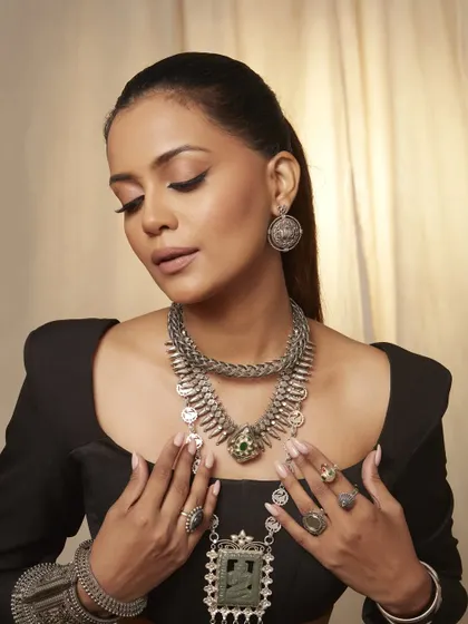 This image showcases the full set of jewelry. The makeup is designed to be the perfect canvas, with soft, defined eyes and glowing skin that complements the silver tones.