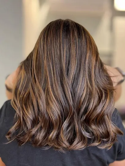 A cinnamon brown balayage that is full of warmth and spice. The highlights are perfectly placed to create a beautiful, flowing look.