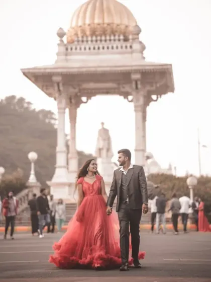 A couple enjoys a walk during their pre-wedding shoot. Our red ruffled gown adds a vibrant pop of color to this city scene.