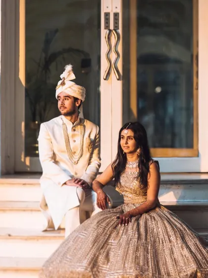 A regal portrait of the couple seated on the steps of the palace hotel. The golden hour light adds a warm, magical glow to the scene.