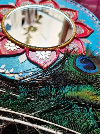 A close-up detail shot of the lotus Lippan art mirror with peacock feathers.