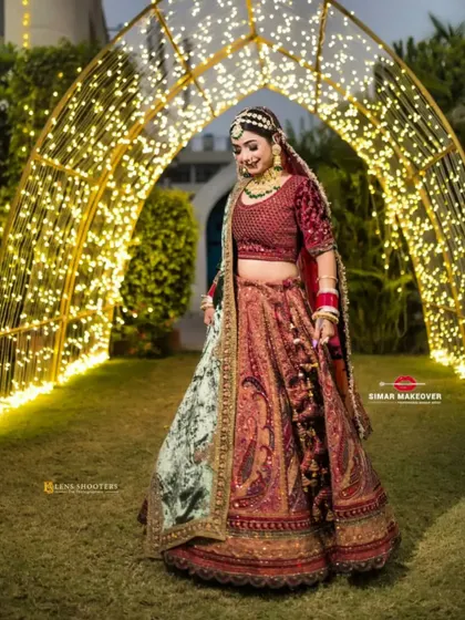 The full glory of this velvet bridal lehenga, captured under beautiful lighting. The fairy lights in the background add to the magical feel of a wedding night.