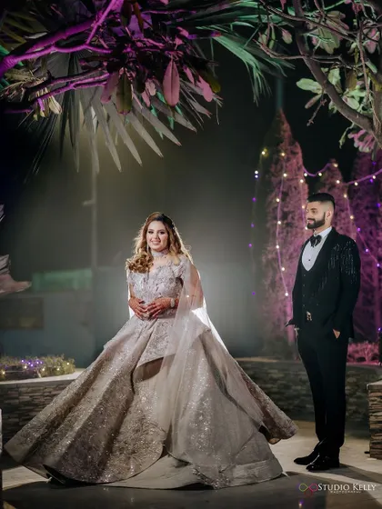 A stylish portrait of the couple at their reception, with the groom looking on as the bride takes center stage.