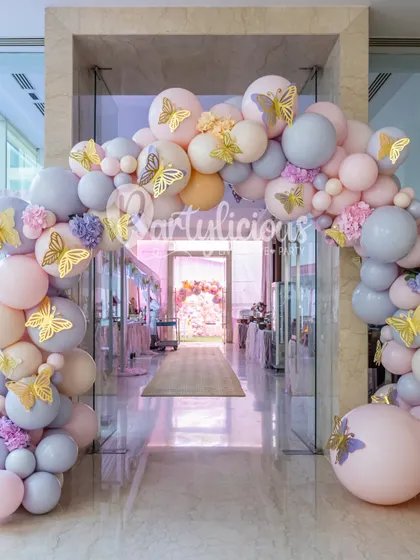 A breathtaking balloon arch in pastel pink and lilac, adorned with golden butterflies, creating a grand and magical entryway.
