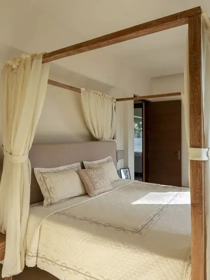 A serene bedroom with a four-poster bed and light, airy curtains, creating a romantic and restful atmosphere.