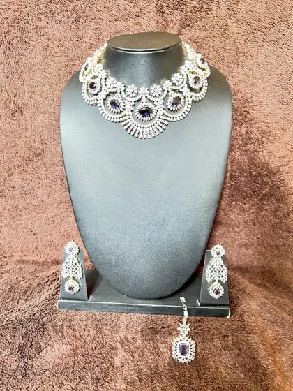 A simple yet elegant CZ stone choker set with purple stones. This rental includes a necklace, matching earrings, and a maang tikka.