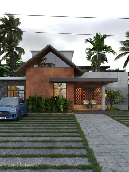 This Kasargod project features a rust-colored textured wall, a gabled roof with a glass front, and a decorative jali screen at the entrance.