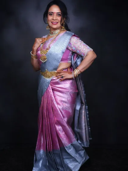 A full-length view showcasing the complete look. The saree draping is done to flatter the figure, complemented by a statement waist belt and traditional jewelry.