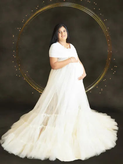 A simple yet elegant portrait in the white cloud gown against a dark backdrop with a golden hoop, creating a modern and artistic look.