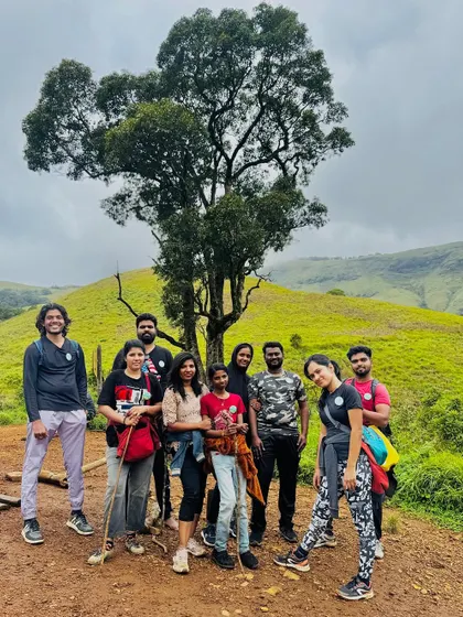 A small group posing under a beautiful tree on the trail.