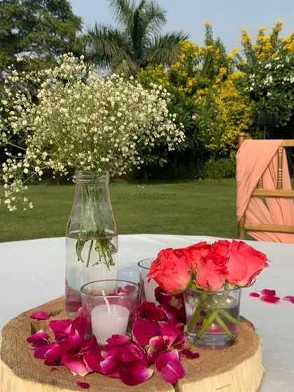 A simple and rustic table centerpiece with roses, baby's breath, and a candle on a wooden slice.