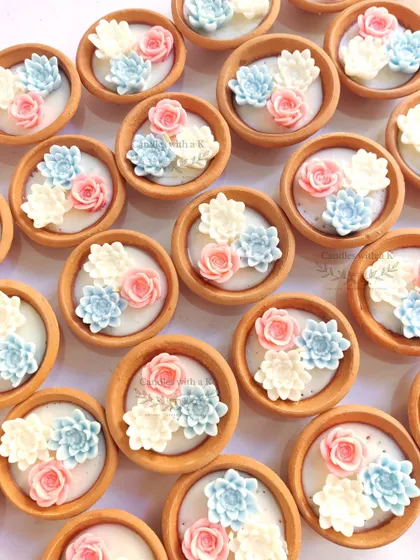 A closer look at the succulent clay pot candles in pink, blue, and white, a popular choice for elegant baby shower favors.