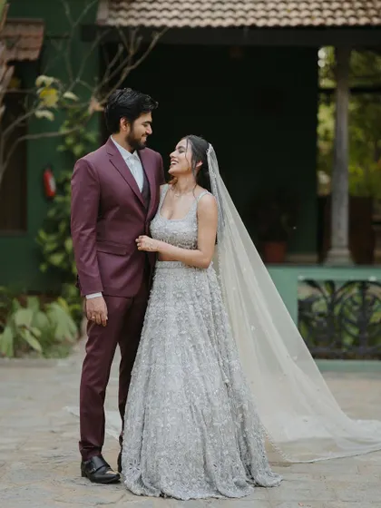 A modern couple, the bride in a stunning silver lehenga, shares a happy moment in the courtyard.