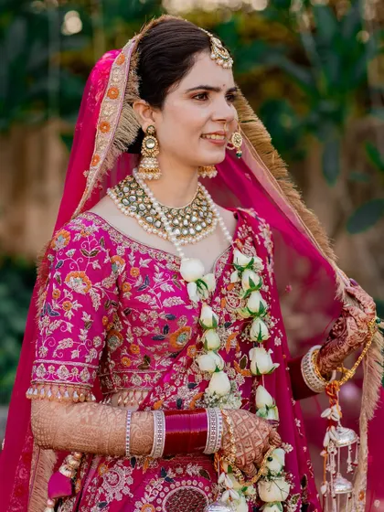 A beautiful close-up of the bride on her wedding day, capturing her natural smile and the intricate embroidery of her pink lehenga.