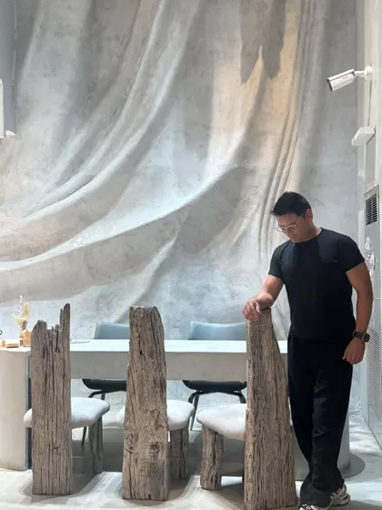 Here I am in the showroom, standing beside chairs crafted from weathered, reclaimed wood logs. Every piece in this project was envisioned as a sculpture, designed to be both functional and a piece of art that tells a story of nature and time.