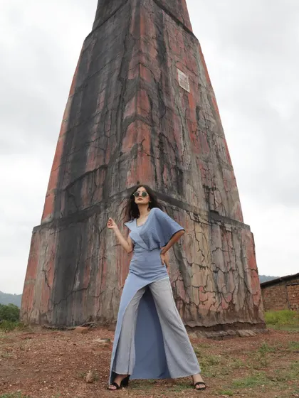 A designer shoot against a rustic, architectural backdrop. I styled this blue jumpsuit with a unique silhouette to create a strong contrast with the textured, earthy tones of the location.