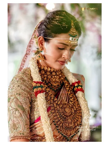 A close-up of Ashitha during the ceremony. The soft lighting highlights the beautiful, natural finish of her makeup, creating a timeless and ethereal bridal portrait.