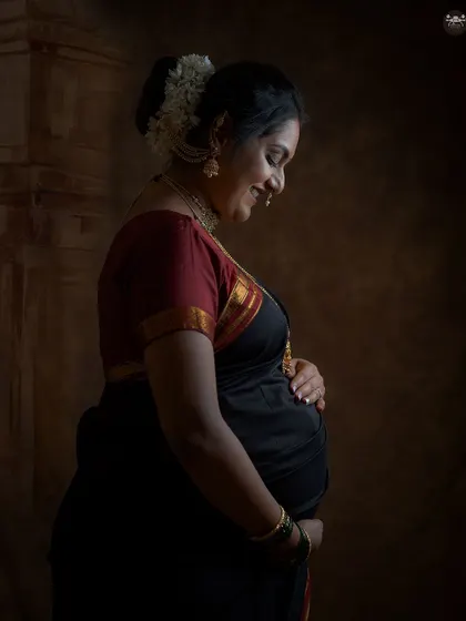 A beautiful profile shot of a mother-to-be cradling her bump. The side lighting sculpts her form, highlighting the beautiful curve of her pregnancy in this fine-art maternity photo.