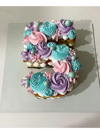 A monogram cake in the shape of the number 5. This strawberry-flavored cake is decorated with beautiful pastel-colored rosettes, perfect for a 5th birthday.